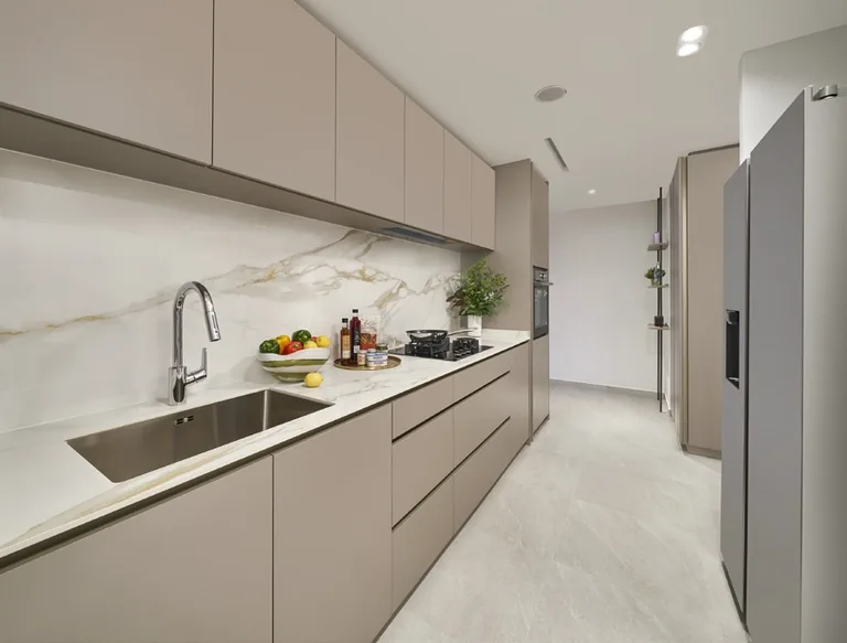 The Orie show-unit interior, for illustration only: a kitchen with handle-less taupe cabinets, a marble-look splashback, an undermount sink and a tall refrigerator