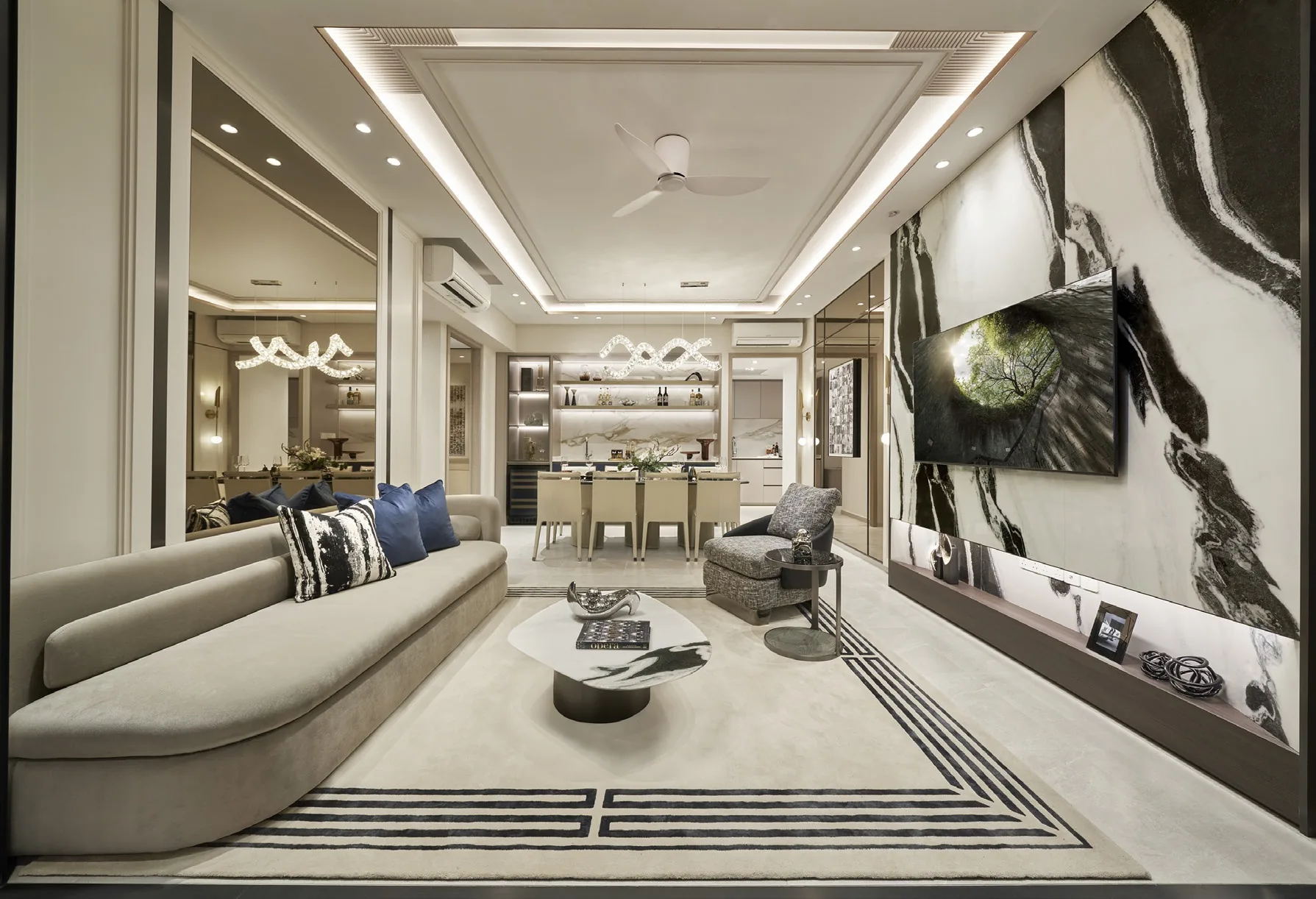 The Orie show-unit interior, for illustration only: a living room with a long curved sofa, a marble feature wall and the dining area beyond under a sculpted light